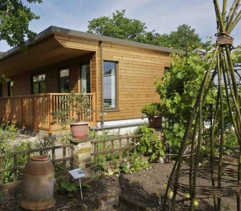 wooden cabin set against planted flowers and vegetables